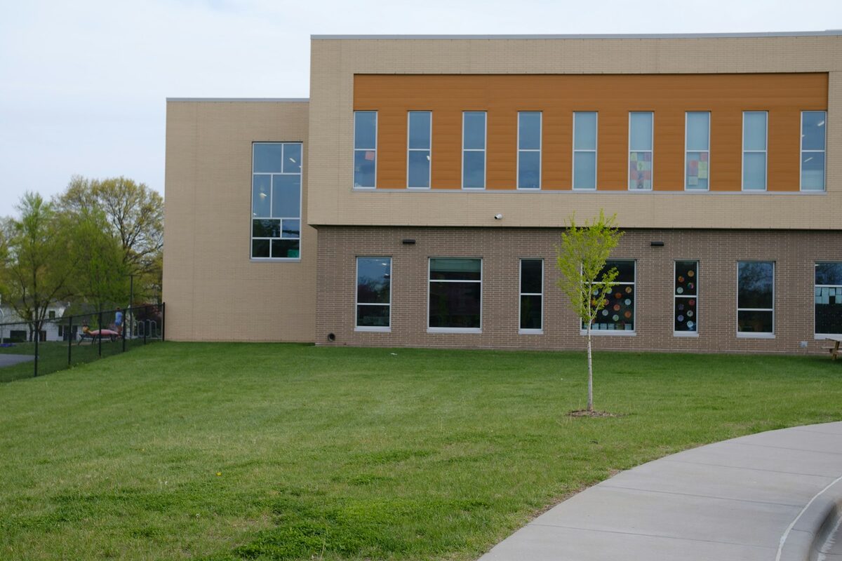 Illustrative modern school building with a green lawn