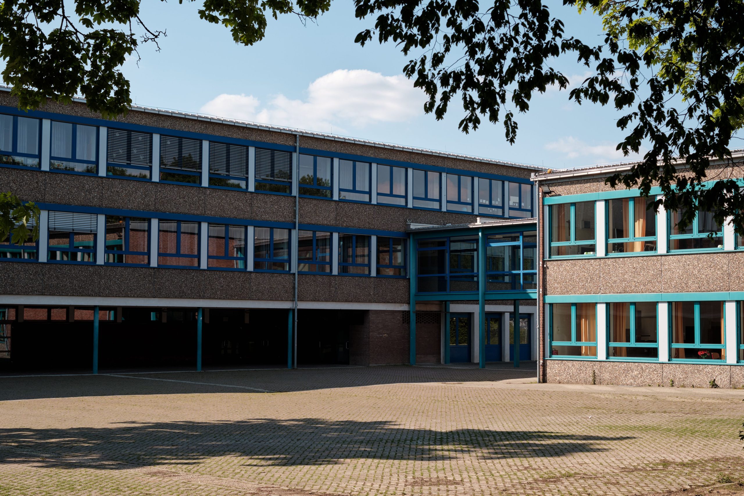 Exterior of a modern school building with a paved courtyard