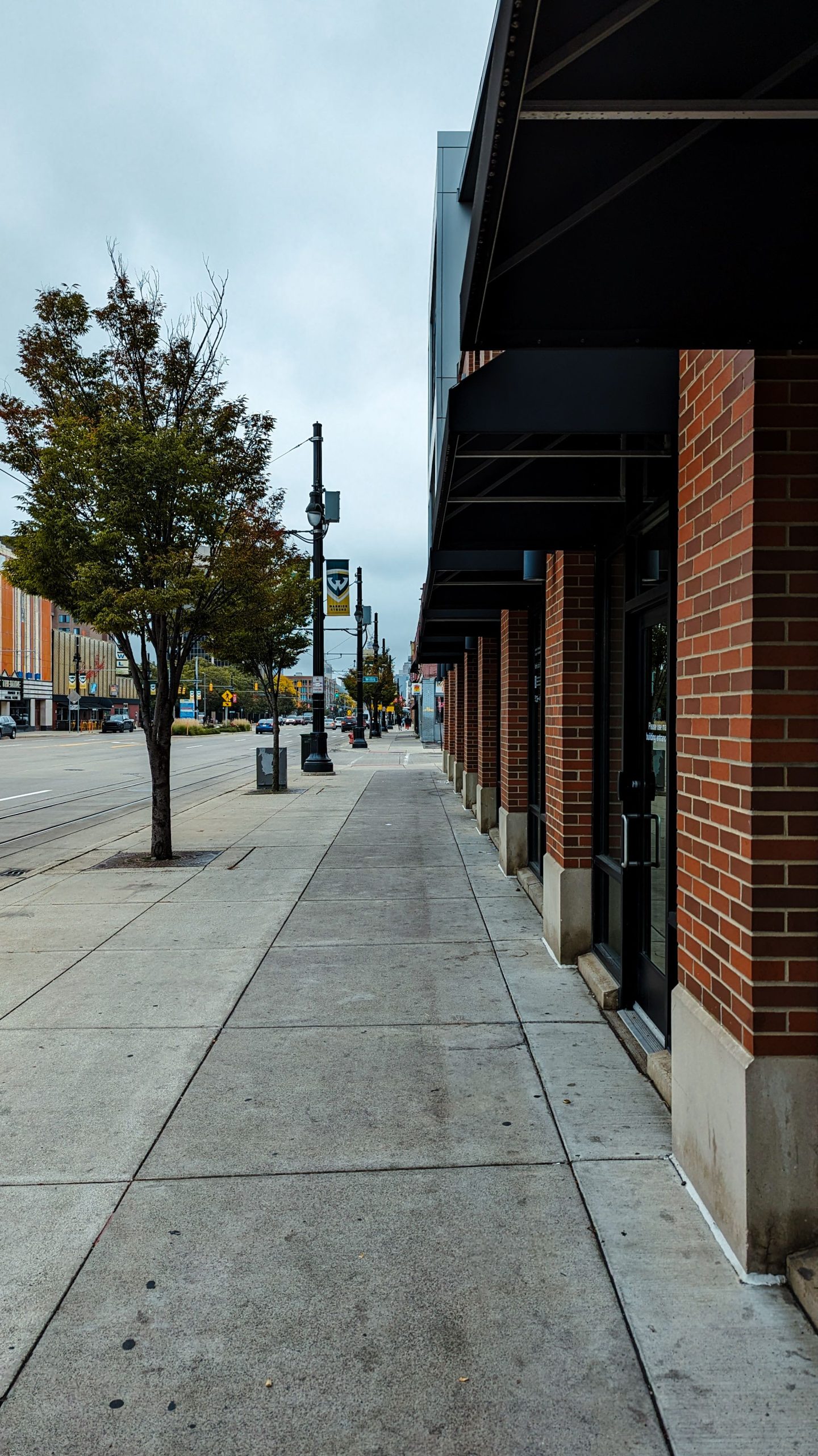 A sidewalk lined with brick storefronts