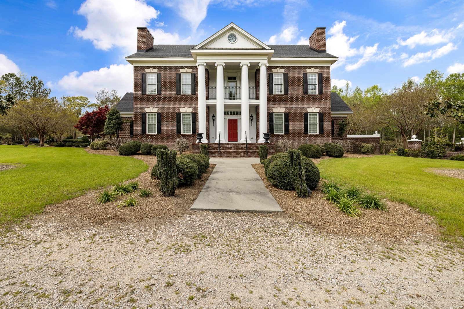 Traditional brick estate with white columned entrance and lawn